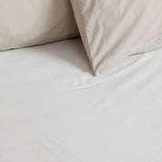 Close-up of beige bed sheets and pillows on a bed.